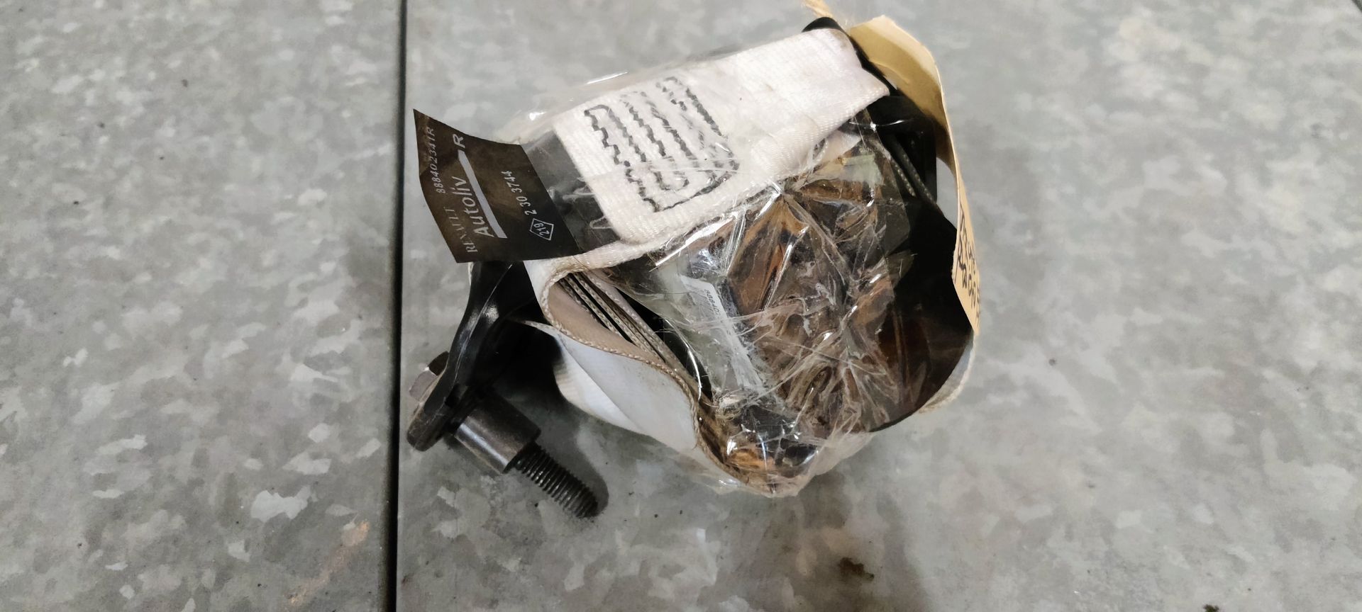 Een beschadigde, witte kartonnen verpakking, omwikkeld met plastic tape, met een klein metalen onderdeel dat aan de onderkant uitsteekt.