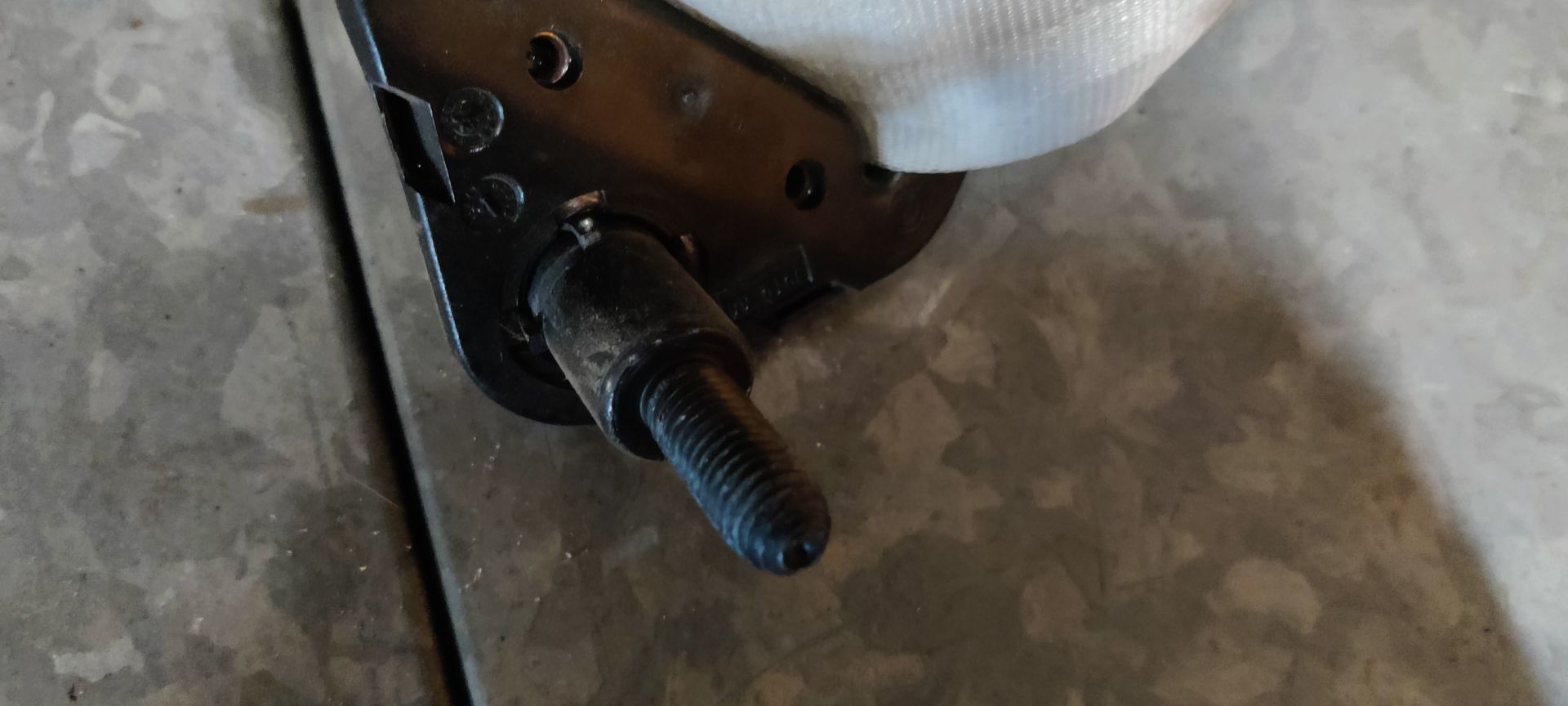 Een beschadigde, witte kartonnen verpakking, omwikkeld met plastic tape, met een klein metalen onderdeel dat aan de onderkant uitsteekt.