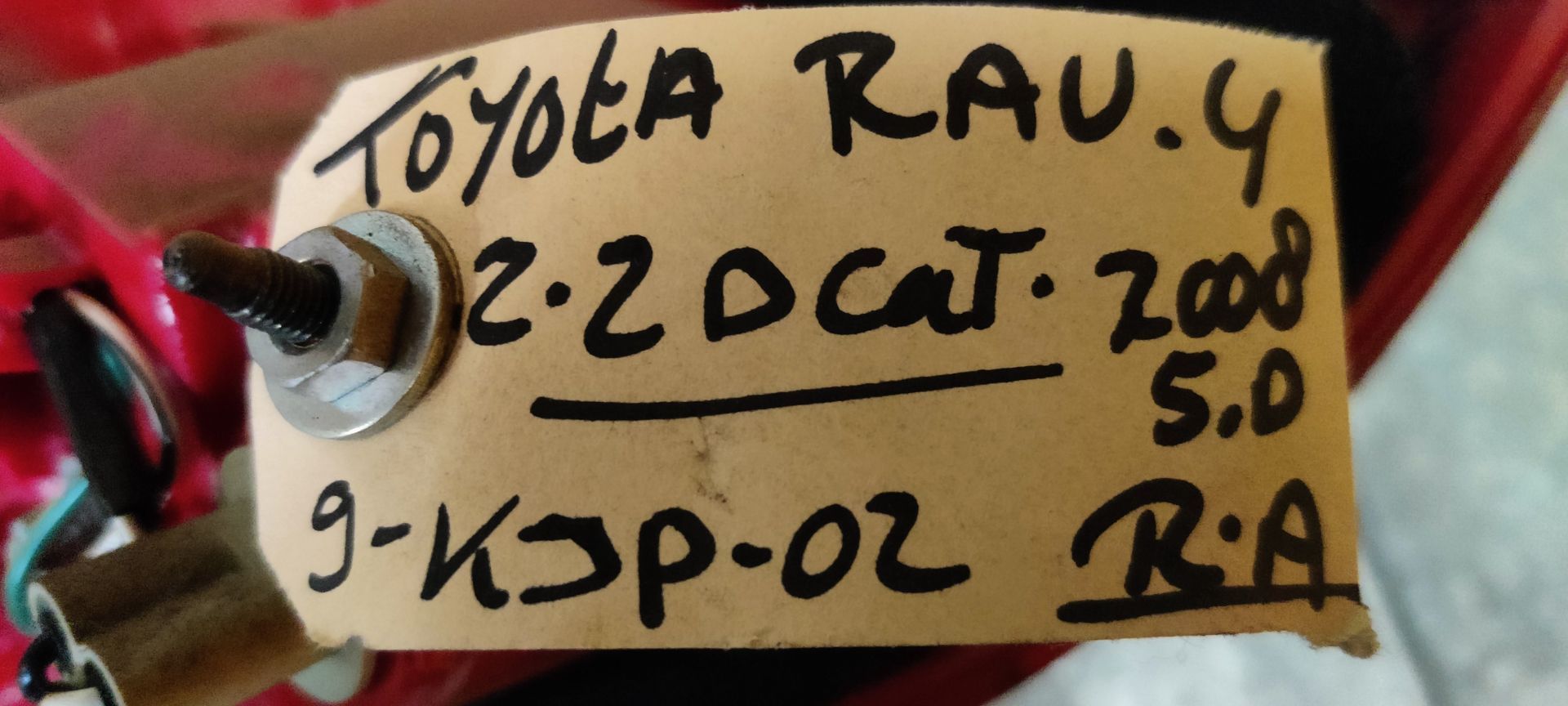 Een rode autoachterlichtunit met een transparant knipperlichtgedeelte, van bovenaf gefotografeerd op een grijze achtergrond.