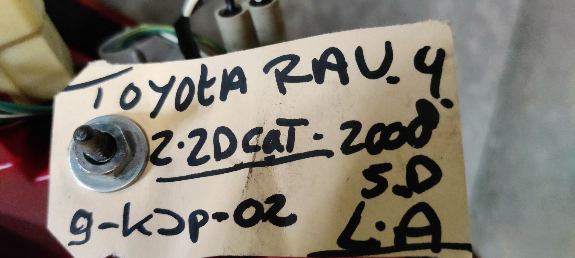 Een achterlichtunit voor auto's met een rode behuizing en transparante delen voor de richtingaanwijzers, rustend op een grijze ondergrond.