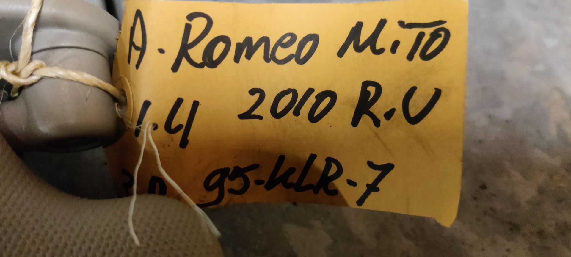 Alfa Romeo MiTo, een beige zonneklep voor in de auto met een waarschuwingslabel, een make-upspiegel met een sticker