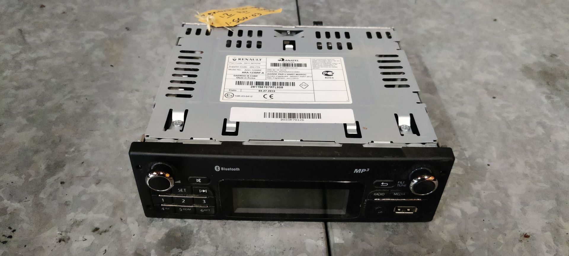 Een autoradio met een zilverkleurige behuizing, een zwart bedieningspaneel en een centraal digitaal display.