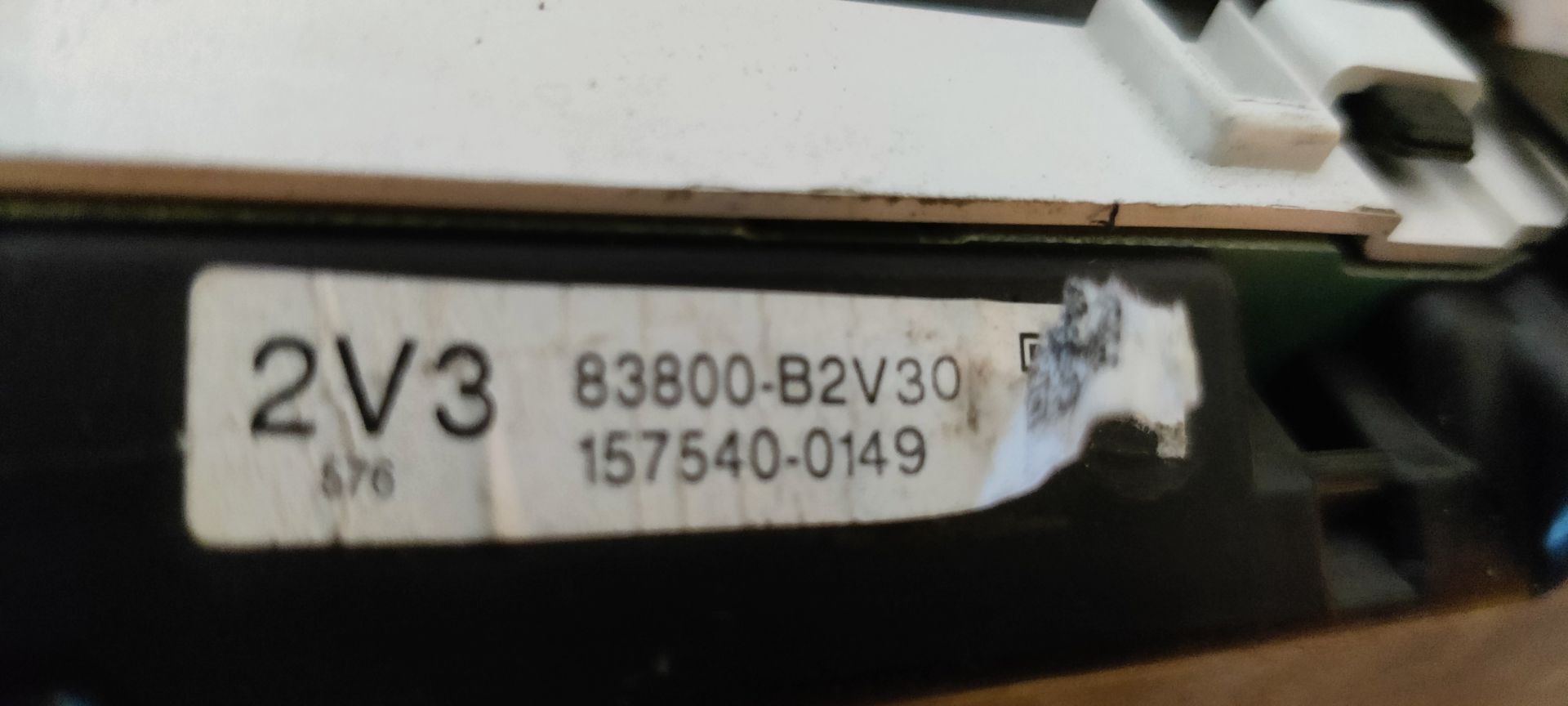 Een ronde snelheidsmeter voor auto's met een zwarte wijzerplaat, witte markeringen en een rode wijzer op een metallic achtergrond.