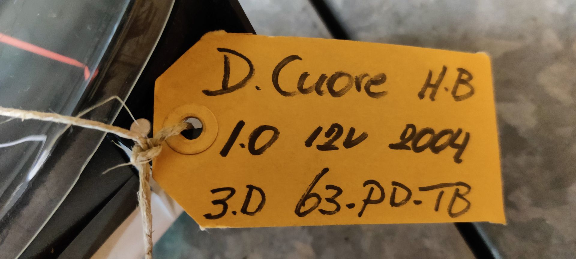 Een instrumentenpaneel van een auto met een snelheidsmeter, brandstofmeter en temperatuurmeter op een neutraal oppervlak met een hangend label.