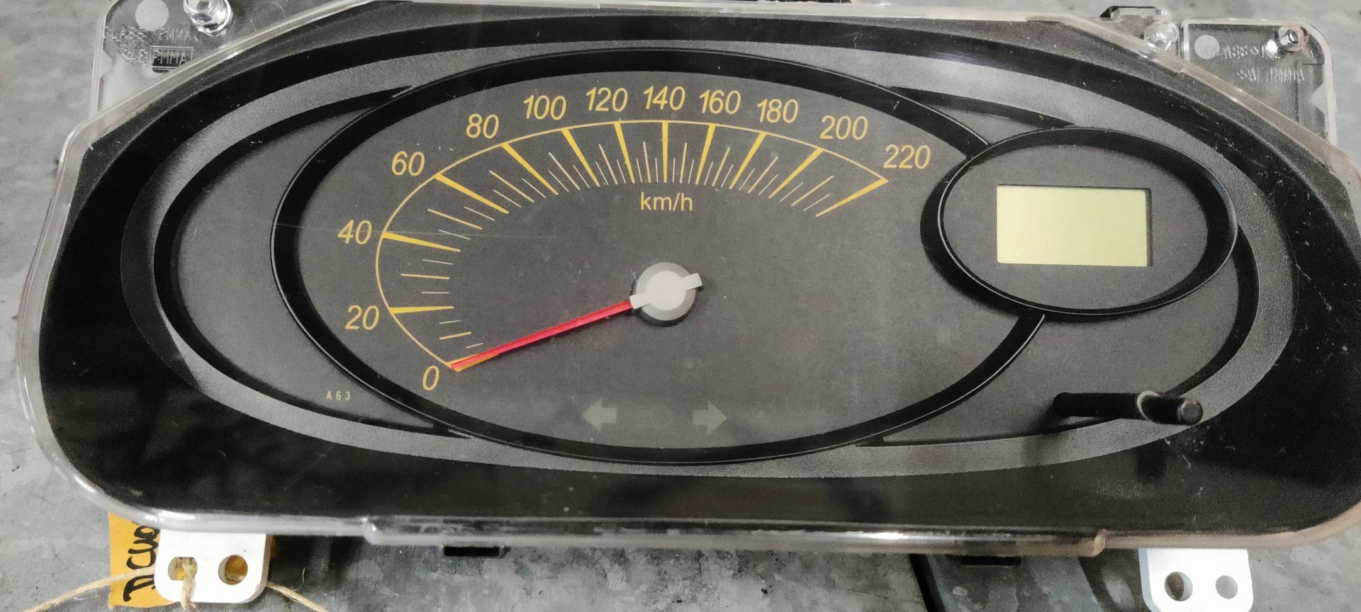 Een zwart dashboard met een snelheidsmeter, gele markeringen van 0 tot 220 km/u, een rode wijzer en een digitaal display.