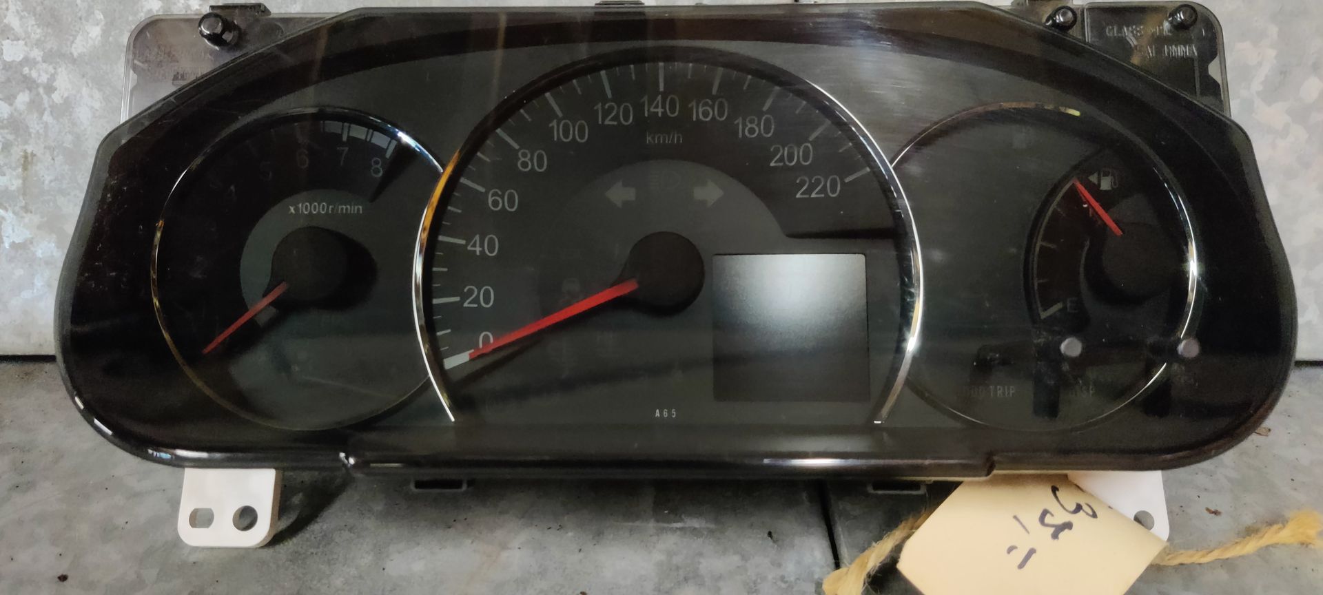 Een zwart instrumentenpaneel voor auto's met een centrale snelheidsmeter, een toerenteller links en een brandstofmeter rechts.