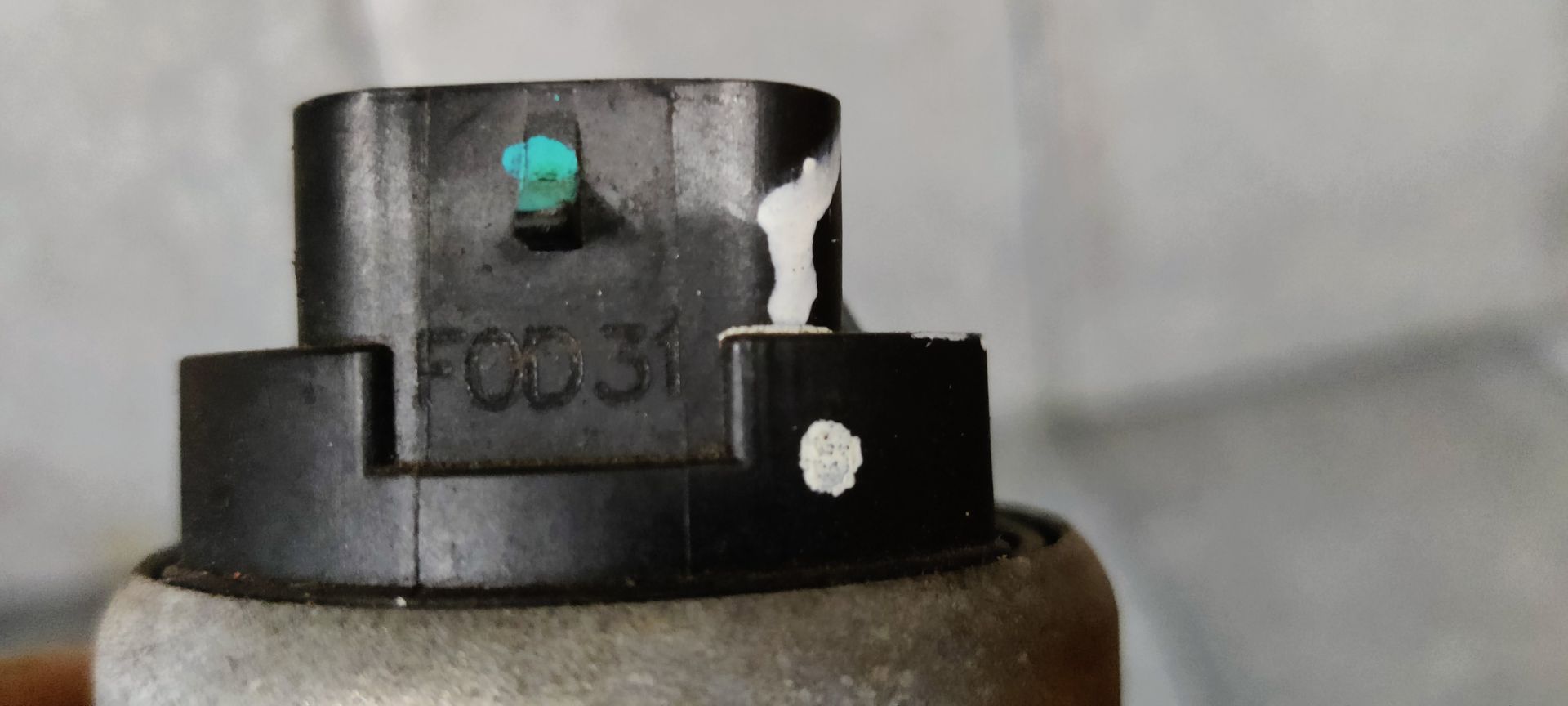 Close-up van een vuile, metalen waterpomphuis voor auto's, waarop ronde openingen te zien zijn met tekenen van corrosie en aanslag.