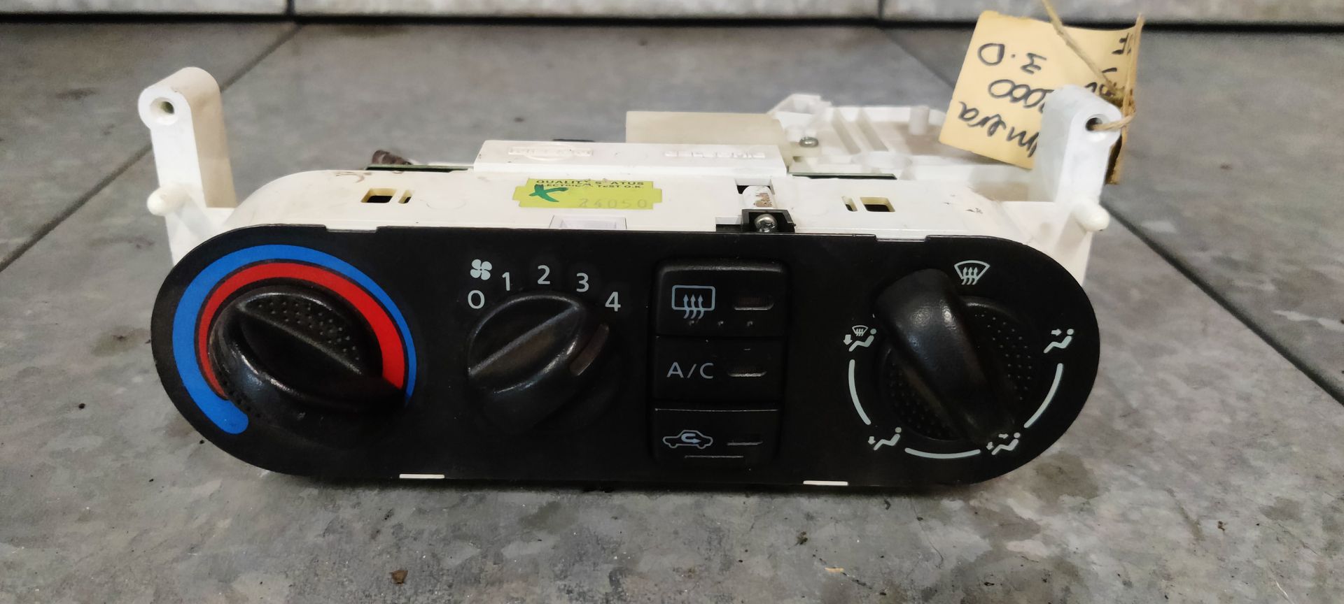 Een zwarte klimaatregelingsunit voor in de auto met draaiknoppen voor temperatuur, ventilatorsnelheid en ventilatie, plus knoppen voor airconditioning en ontwaseming.