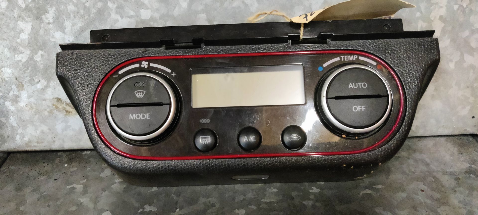 Autoklimaatregelingsmodule met een centraal LCD-scherm, draaiknoppen en drukknoppen, omlijst door een rode rand.