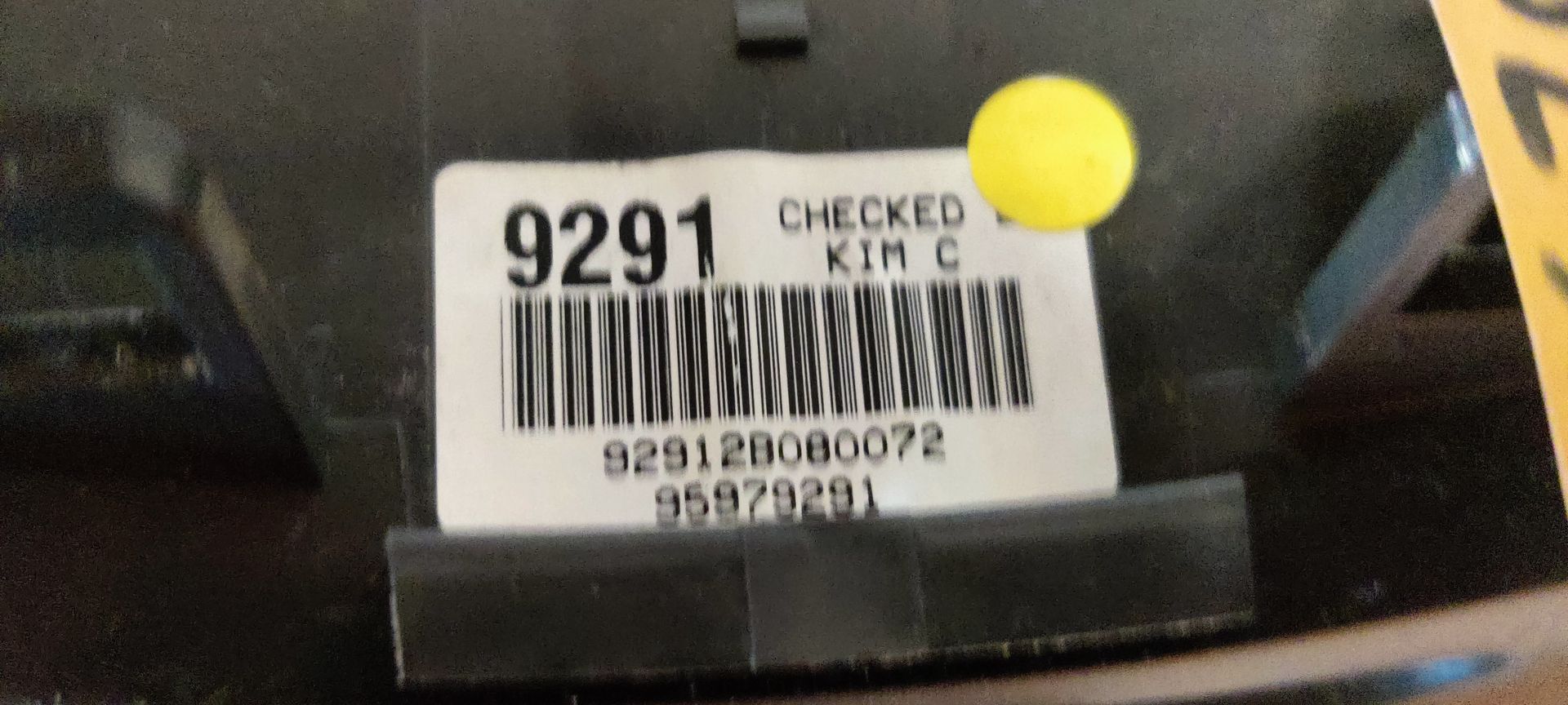 Een donkergrijze klimaatregelingsunit voor een voertuig met drie ronde verstelknoppen en een schuifschakelaar, geïsoleerd op een tegelvloer.