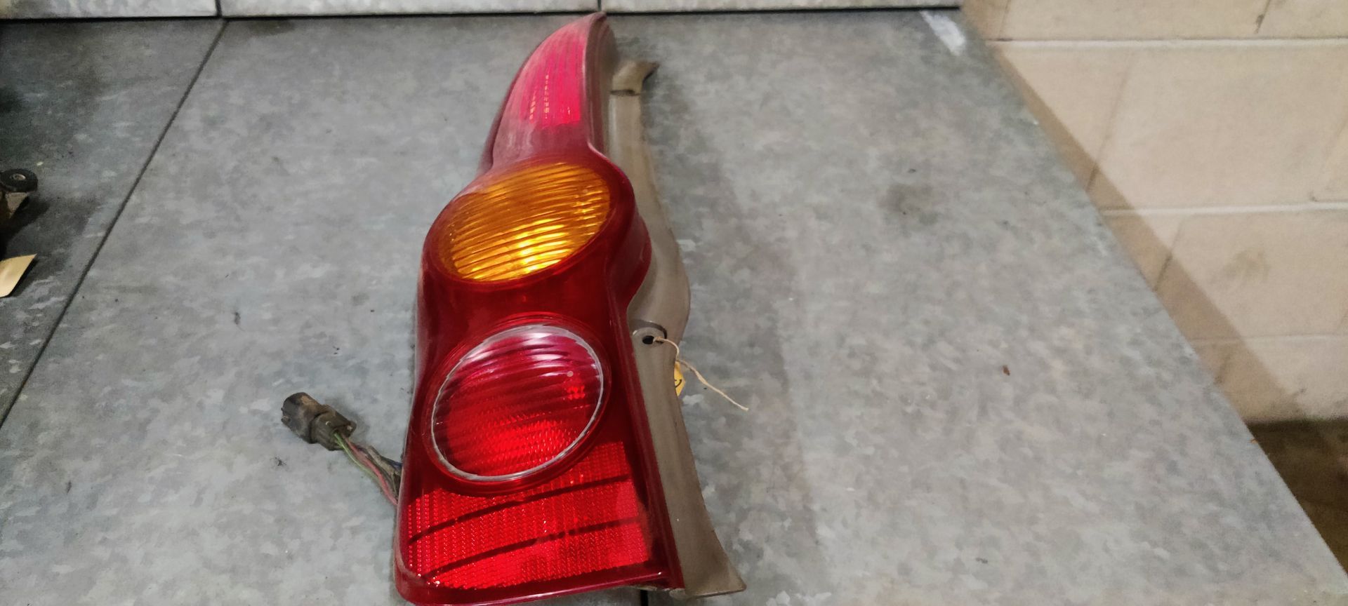 Een rood-oranje autoachterlichtunit, rustend op een grijze werkbank.