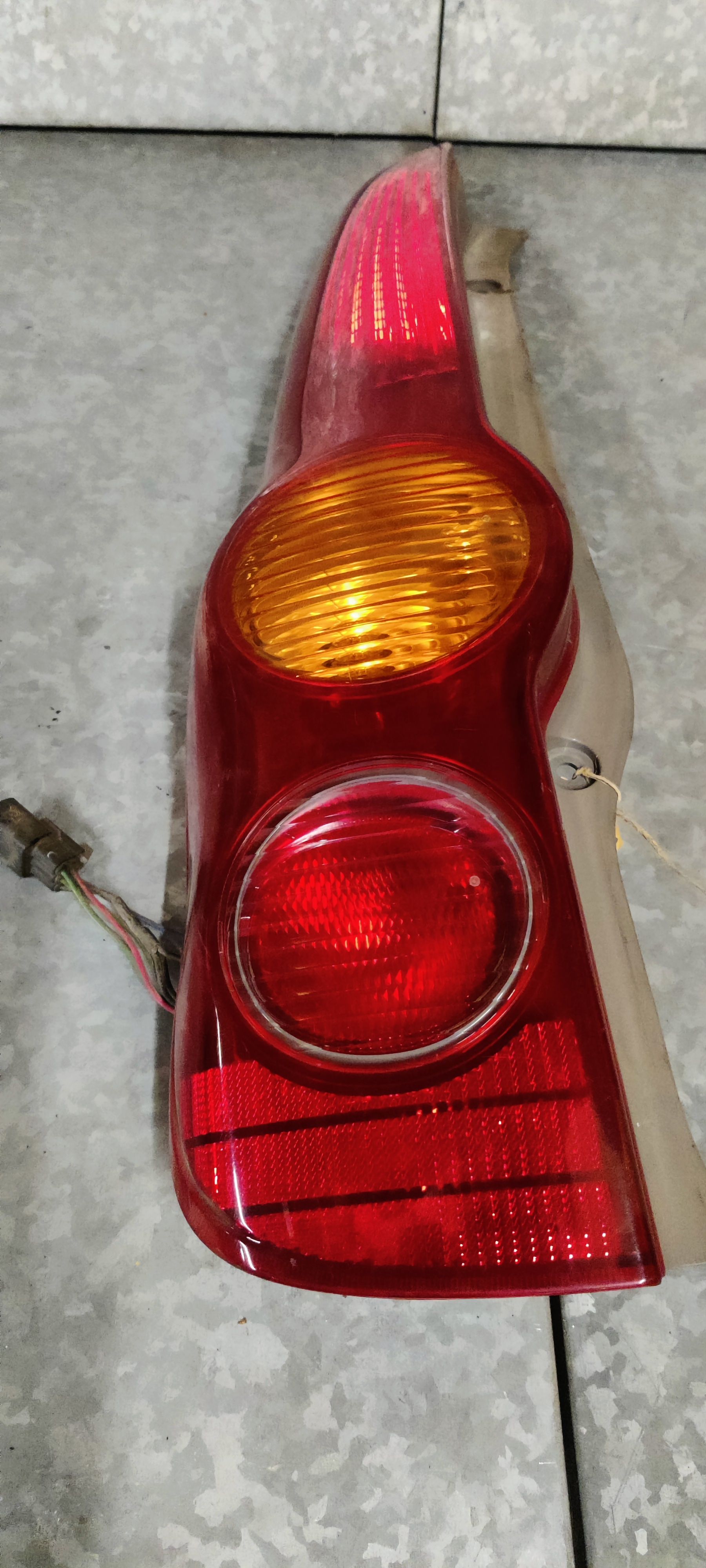 Een rood-oranje autoachterlichtunit, rustend op een grijze werkbank.