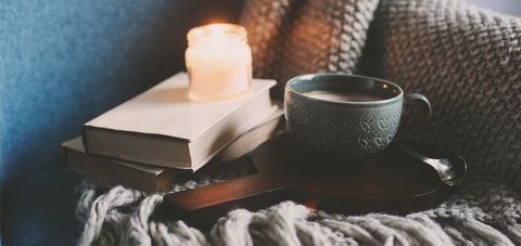Coffee and blanket next to a candle in the bedroom