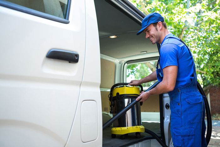 a man in a blue uniform is cleaning a van