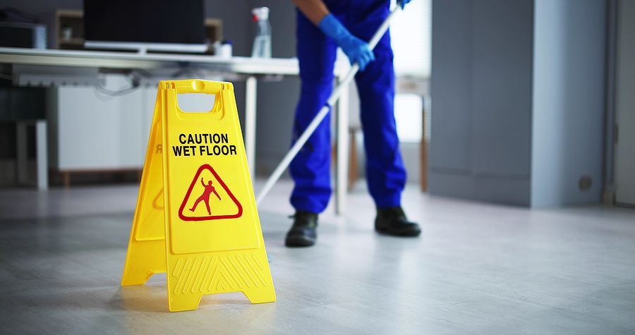 a man with a mop and a caution wet floor sign