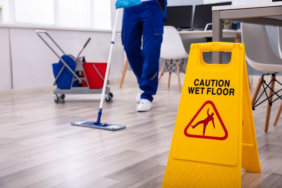 a person with a mop and a caution wet floor sign
