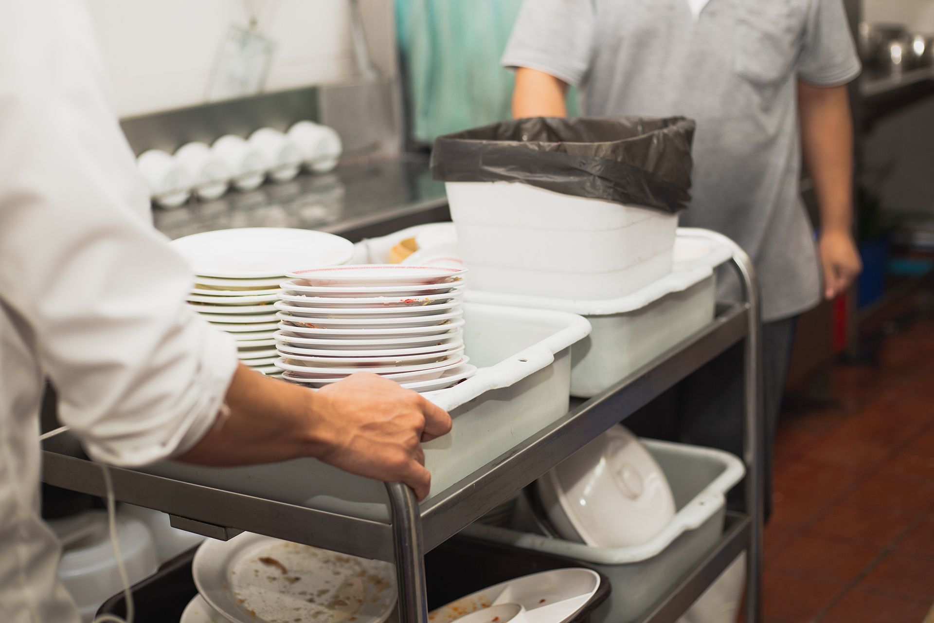 two people in a kitchen preparing plates and bowls
