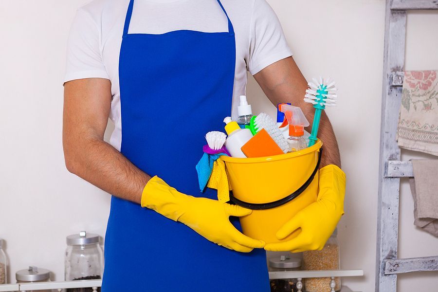 a man in an apron holding a bucket of cleaning supplies