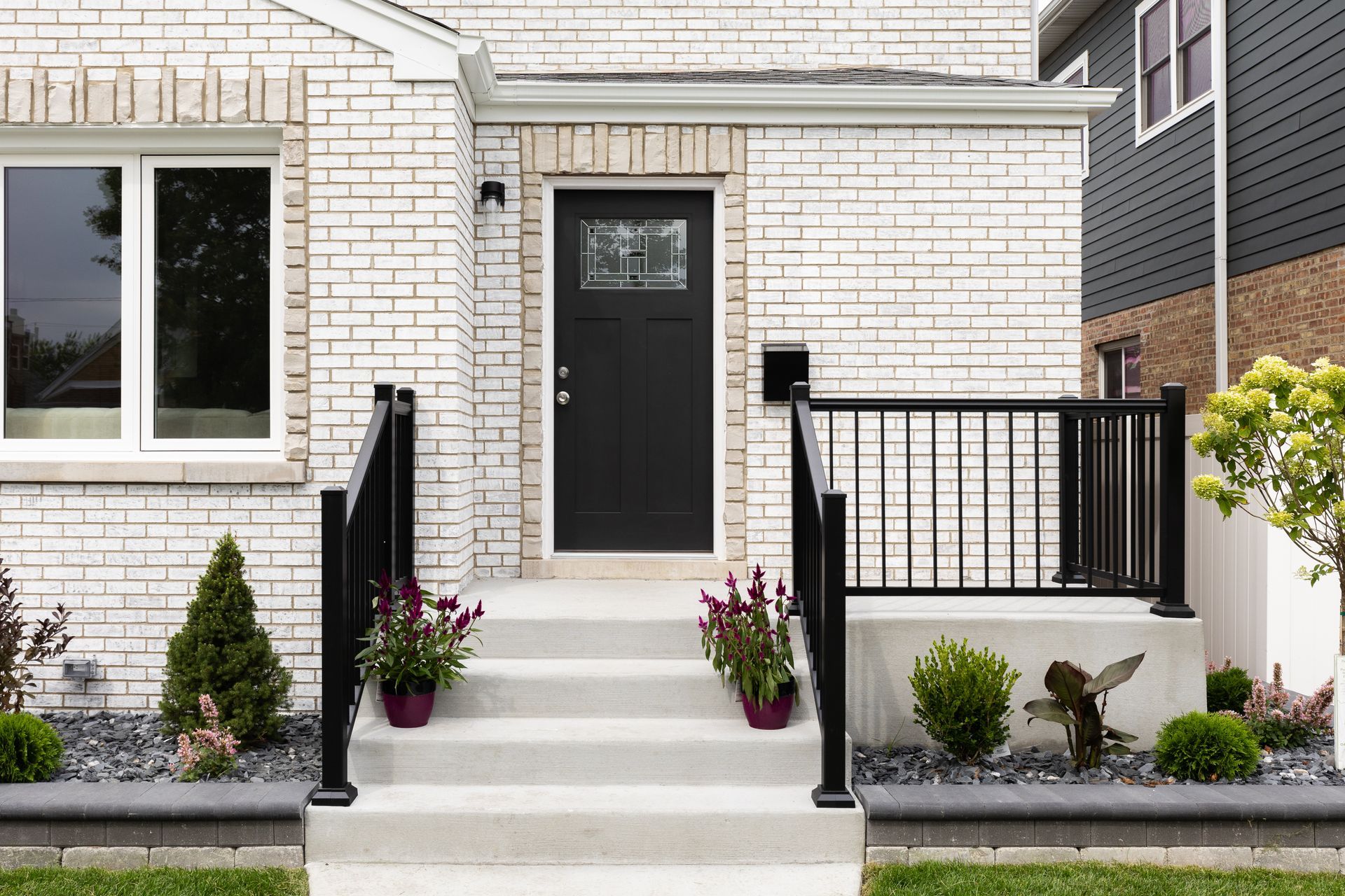 White brick house with black door, steps, and railing