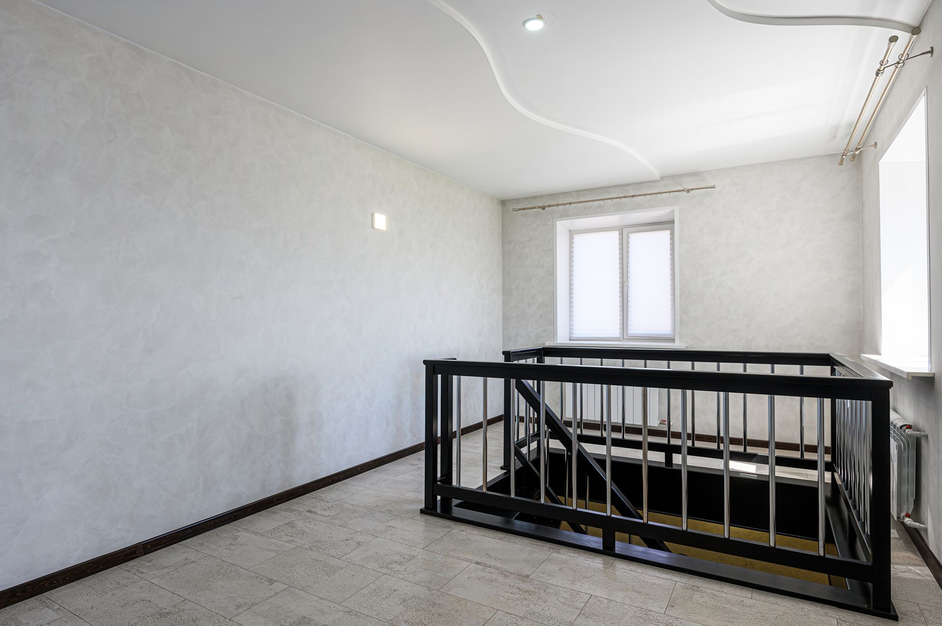 Empty room with a black railing surrounding a staircase Empty room with a black railing surrounding a staircase