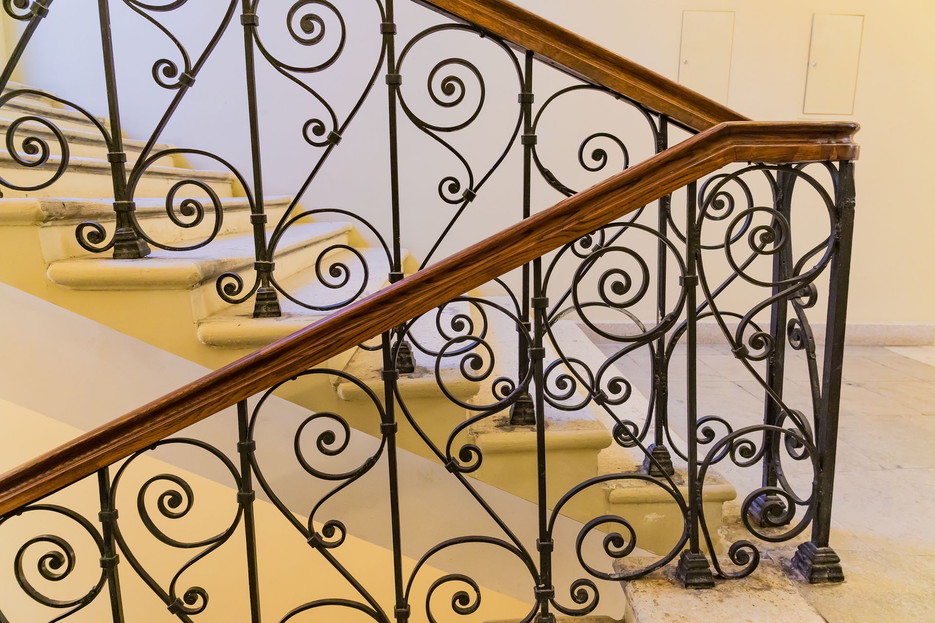 Ornate black wrought iron staircase railing with a wood handrail Ornate black wrought iron staircase railing with a wood handrail