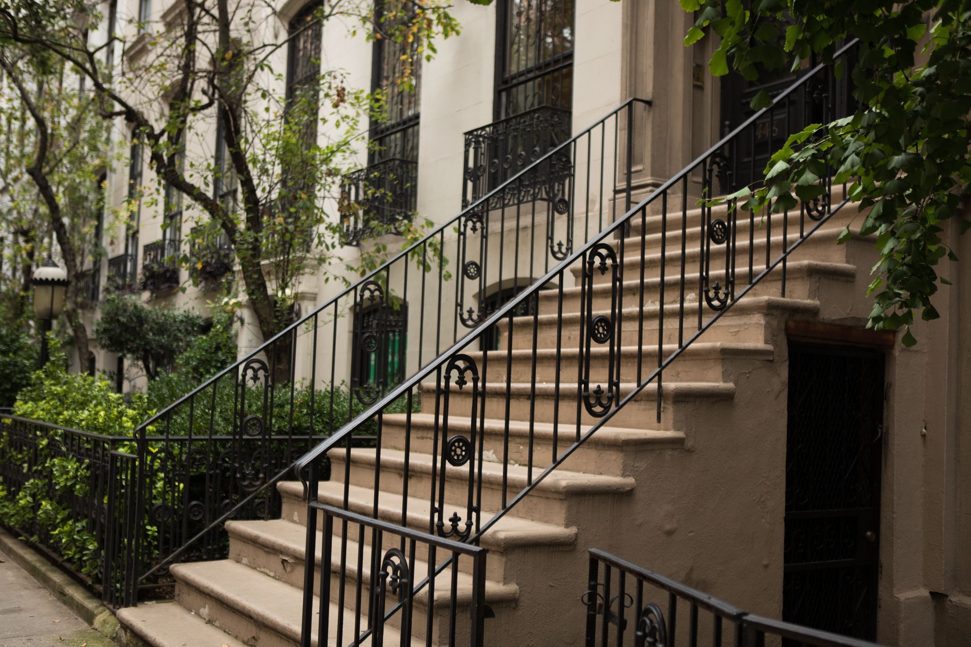 Exterior view of tan steps with black iron railings leading up to a building entrance