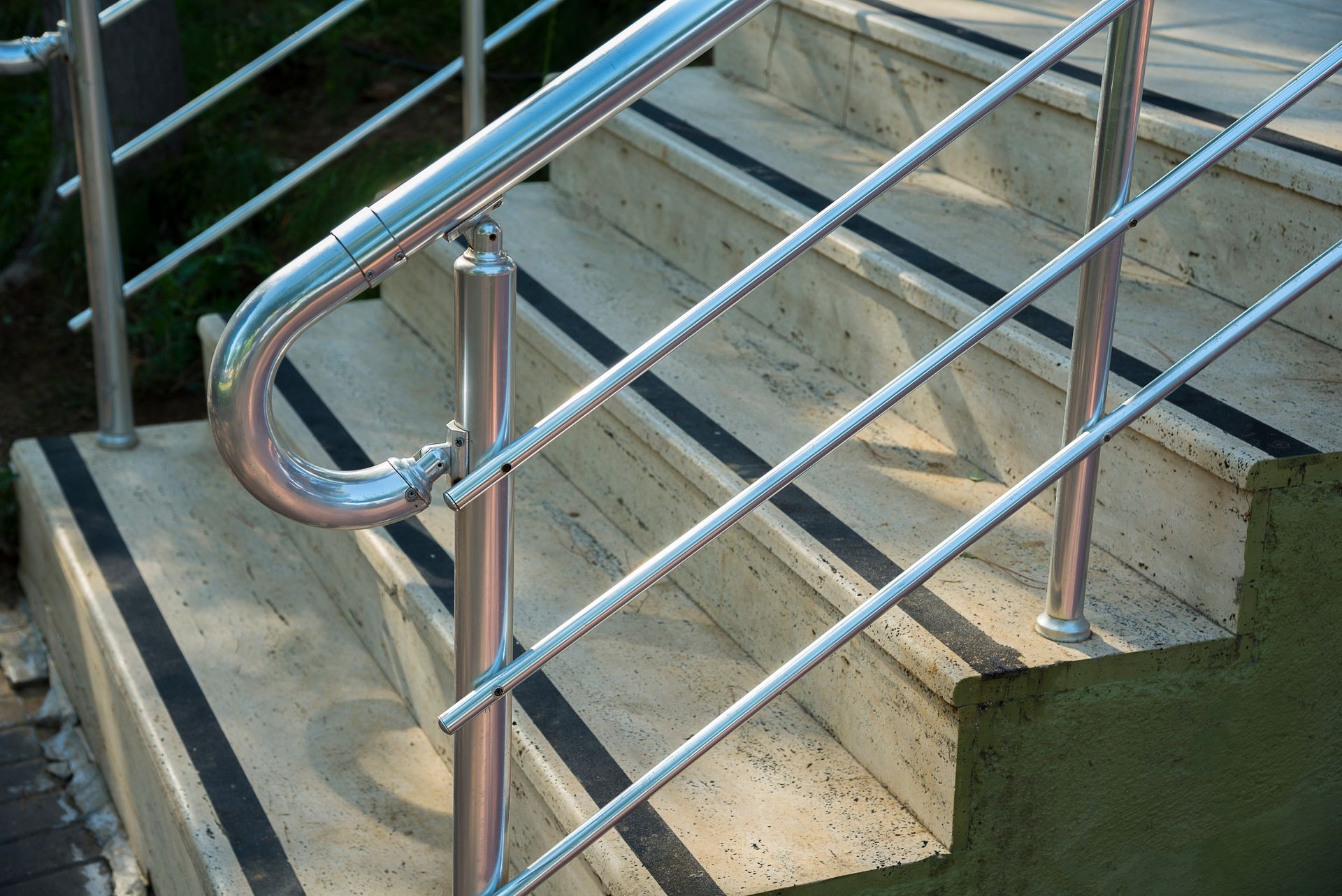 Railing on outdoor concrete stairs with black non-slip strips