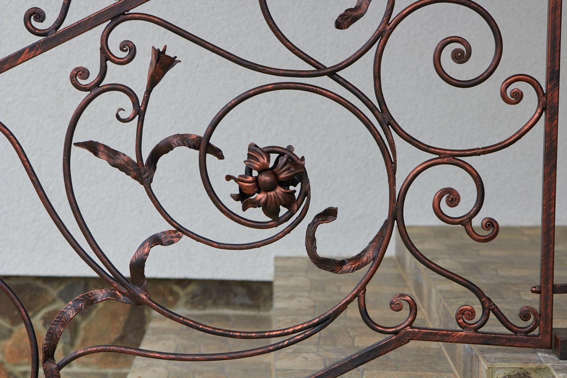 Ornate, copper-colored wrought iron railing with floral and swirl designs Ornate, copper-colored wrought iron railing with floral and swirl designs
