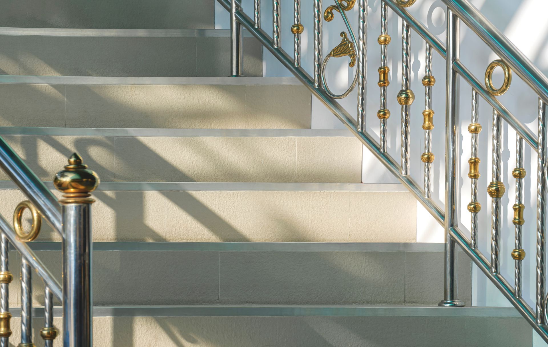 Staircase with light-colored steps, metal railings with gold accents