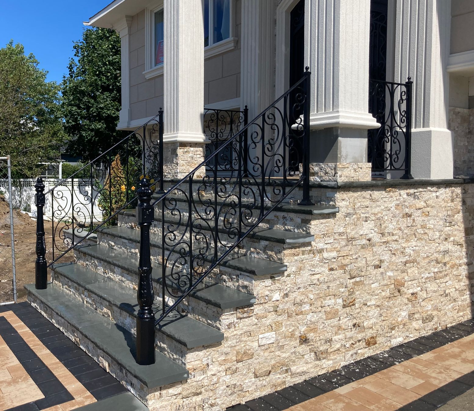 Ornate black metal fence with honeycomb and circular designs, against a building with blue-tinted windows Ornate black metal fence with honeycomb and circular designs, against a building with blue-tinted windows