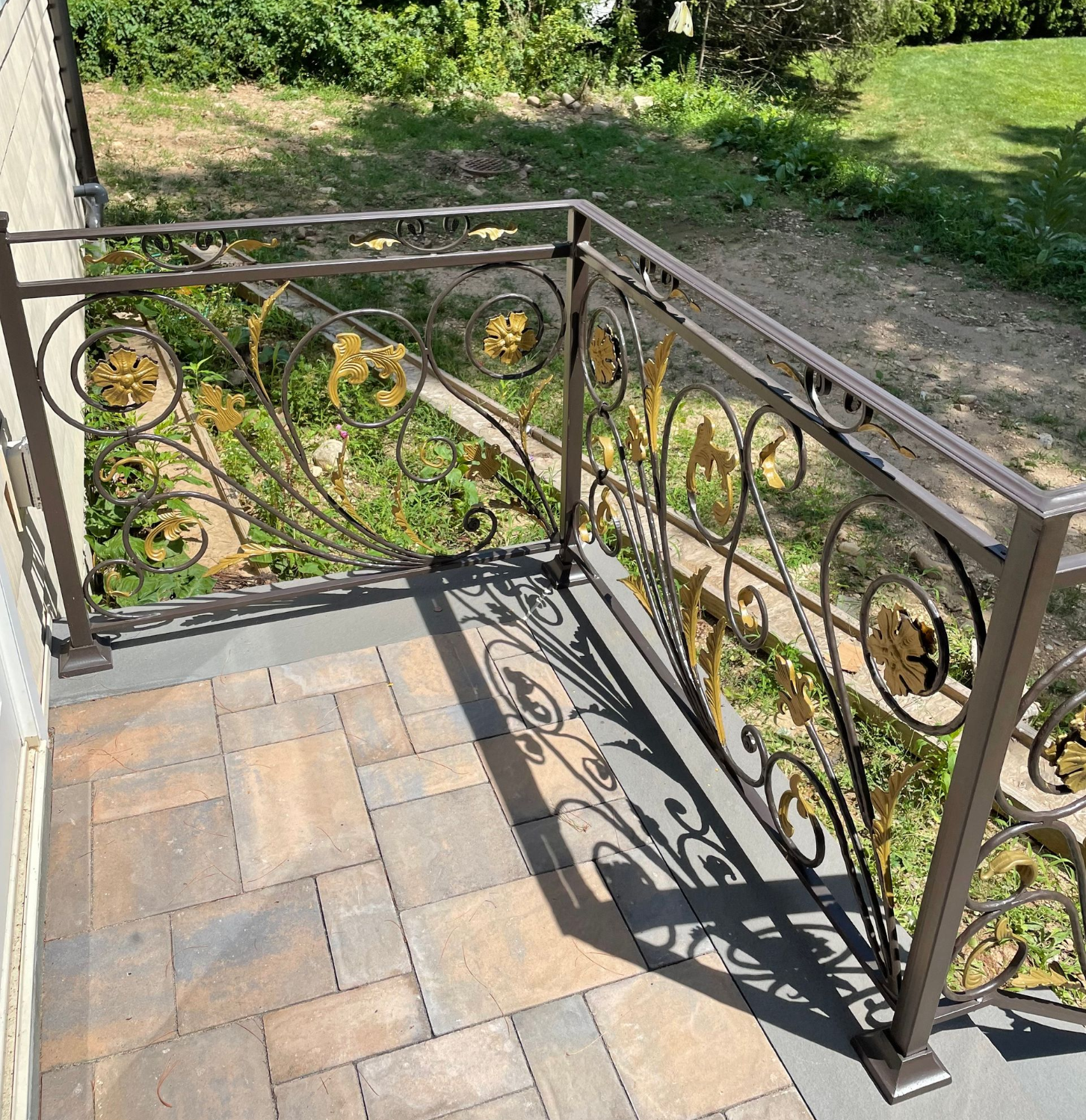 Staircase with ornate black wrought iron railing and a simple handrail on the wall Staircase with ornate black wrought iron railing and a simple handrail on the wall