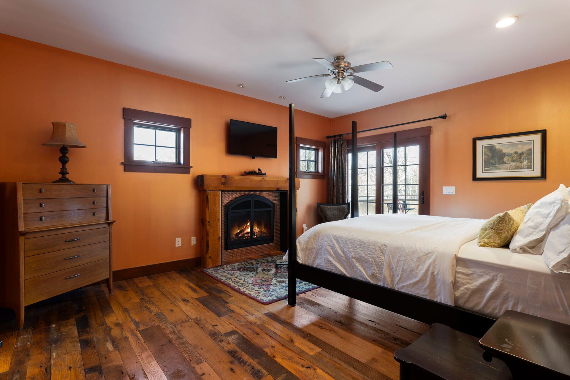Bedroom with light wood bed frame, white bedding, dark green walls, and natural wood floor.