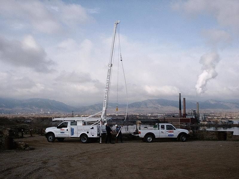 Two white trucks are parked next to each other in a dirt field