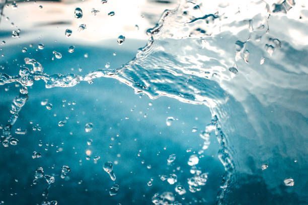Close-up of water splashing with droplets against a blue background.