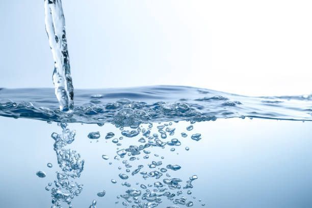 Water being poured into a body of water, creating bubbles and ripples.