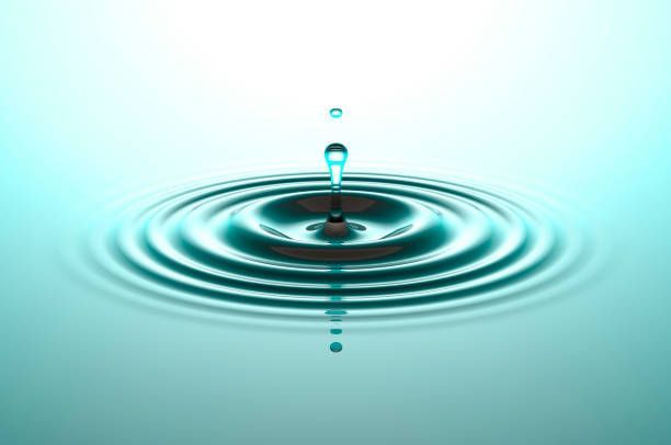 A water droplet falling into a body of water, creating concentric ripples in shades of blue and turquoise.