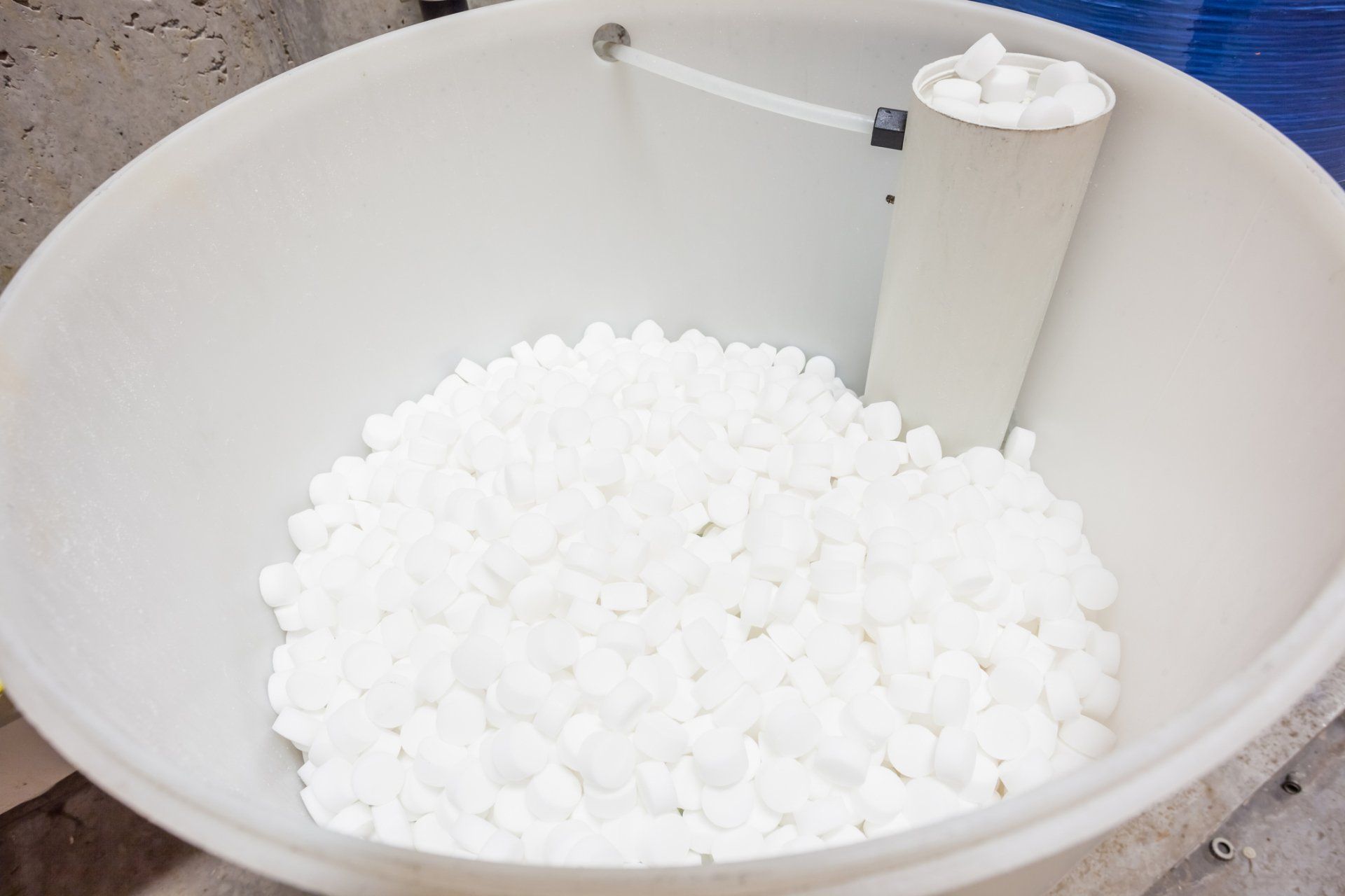 A white bowl filled with white balls next to a pipe.