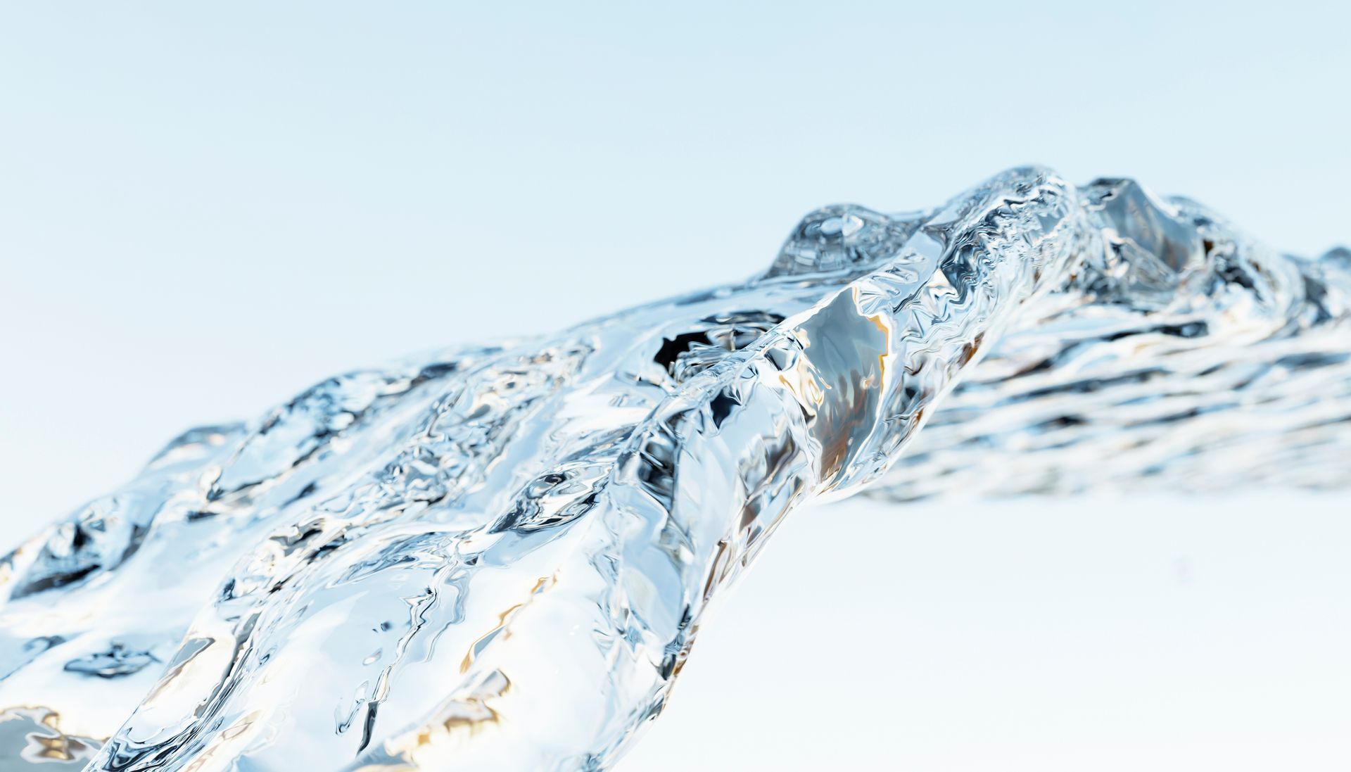 A stream of clear water against a light blue background. The water is partially frozen, showing some texture.