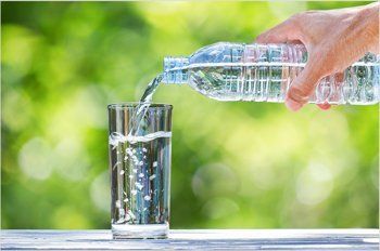 A person is pouring water from a bottle into a glass.