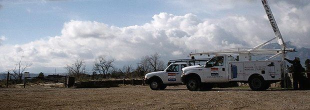 A white truck with a crane on the back is parked in a field.