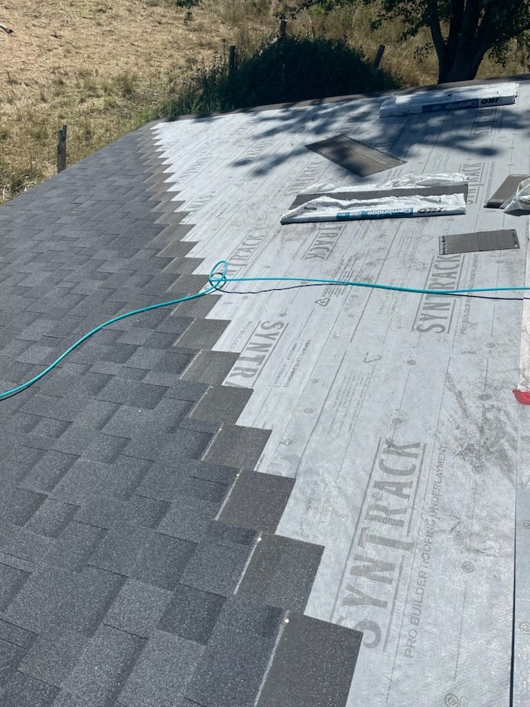 Roof with shingles partially installed, showing gray shingles and gray underlayment.
