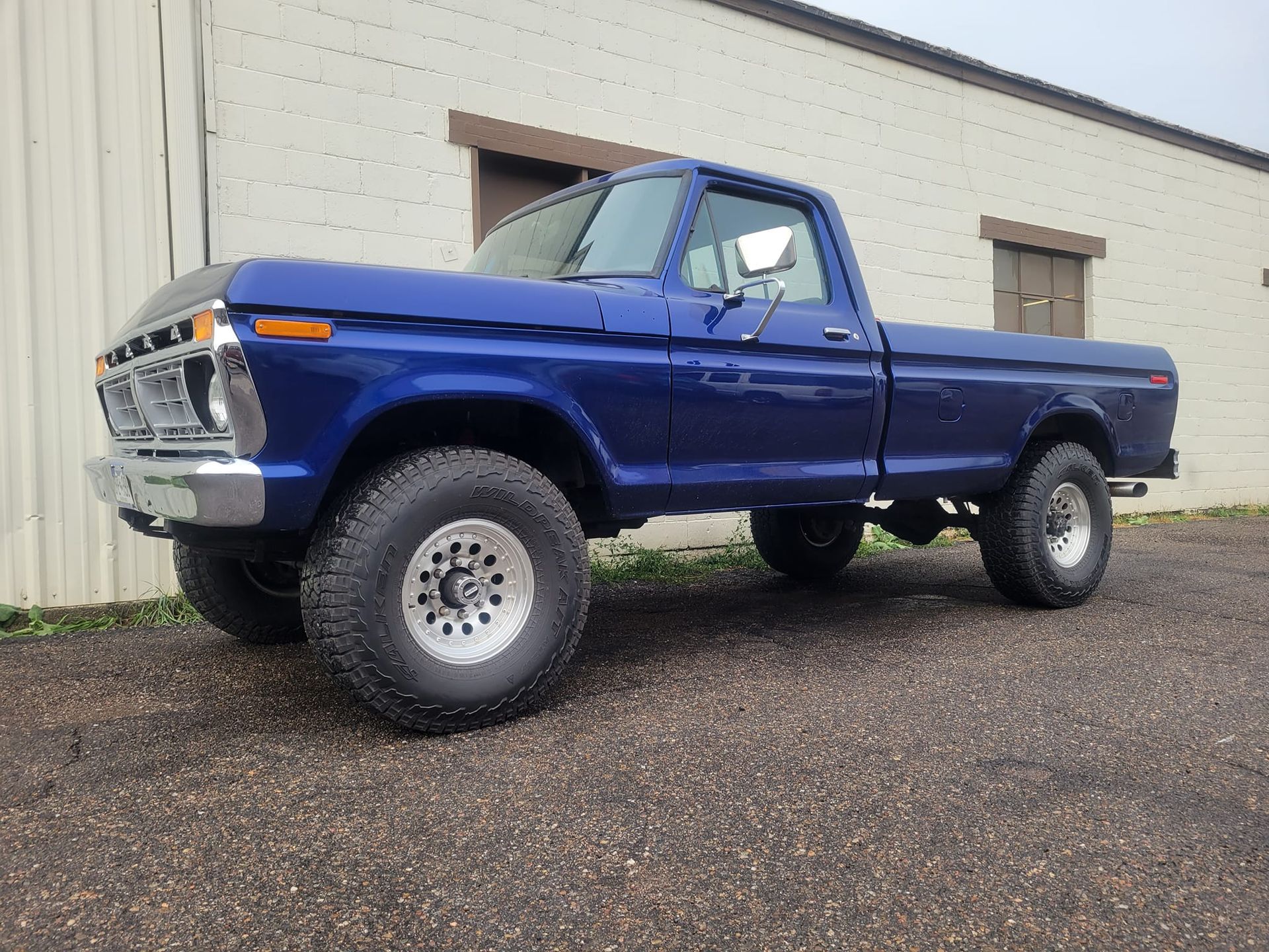 Blue lifted vintage Ford pickup truck parked in front of a building.
