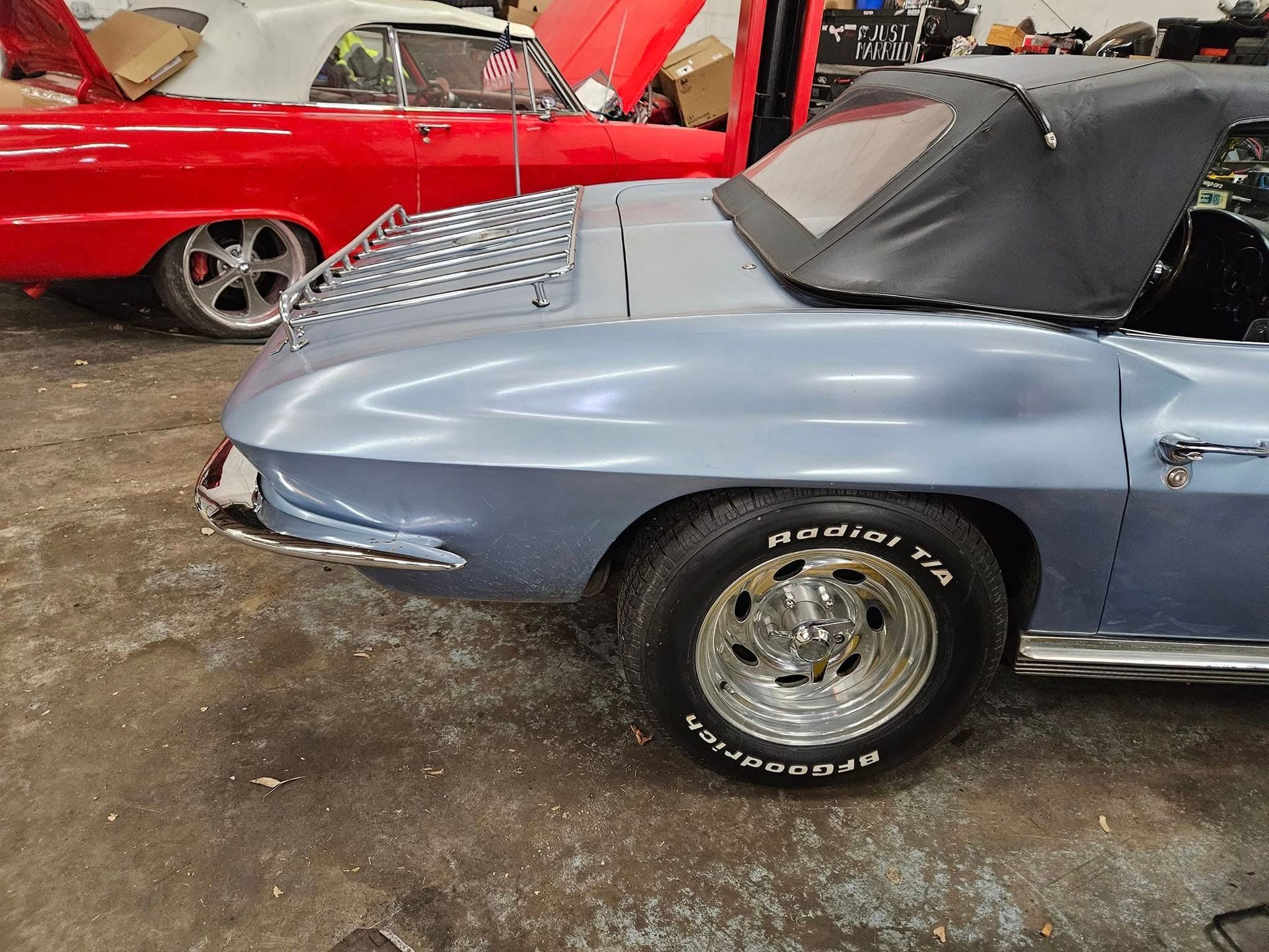 Light blue classic convertible car with black top, chrome wheels, and BFG tires in a garage.
