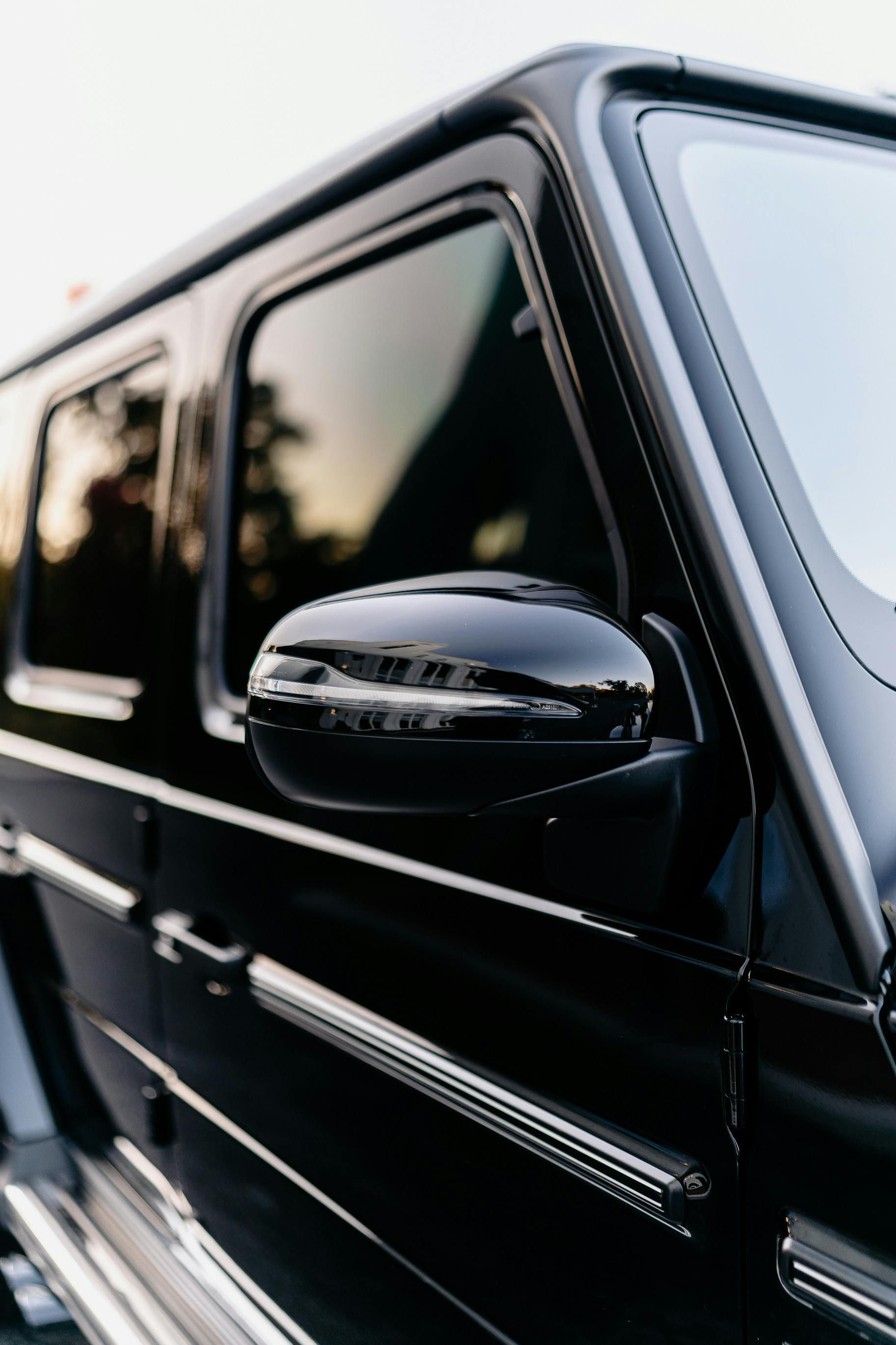 Black Mercedes-Benz G-Wagon side profile, showing window, side mirror, and door handle.