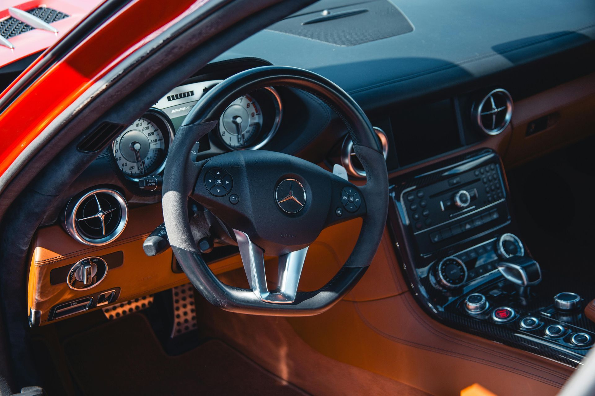 Interior of a red Mercedes-Benz car: dashboard, steering wheel, gauges, and vents visible.