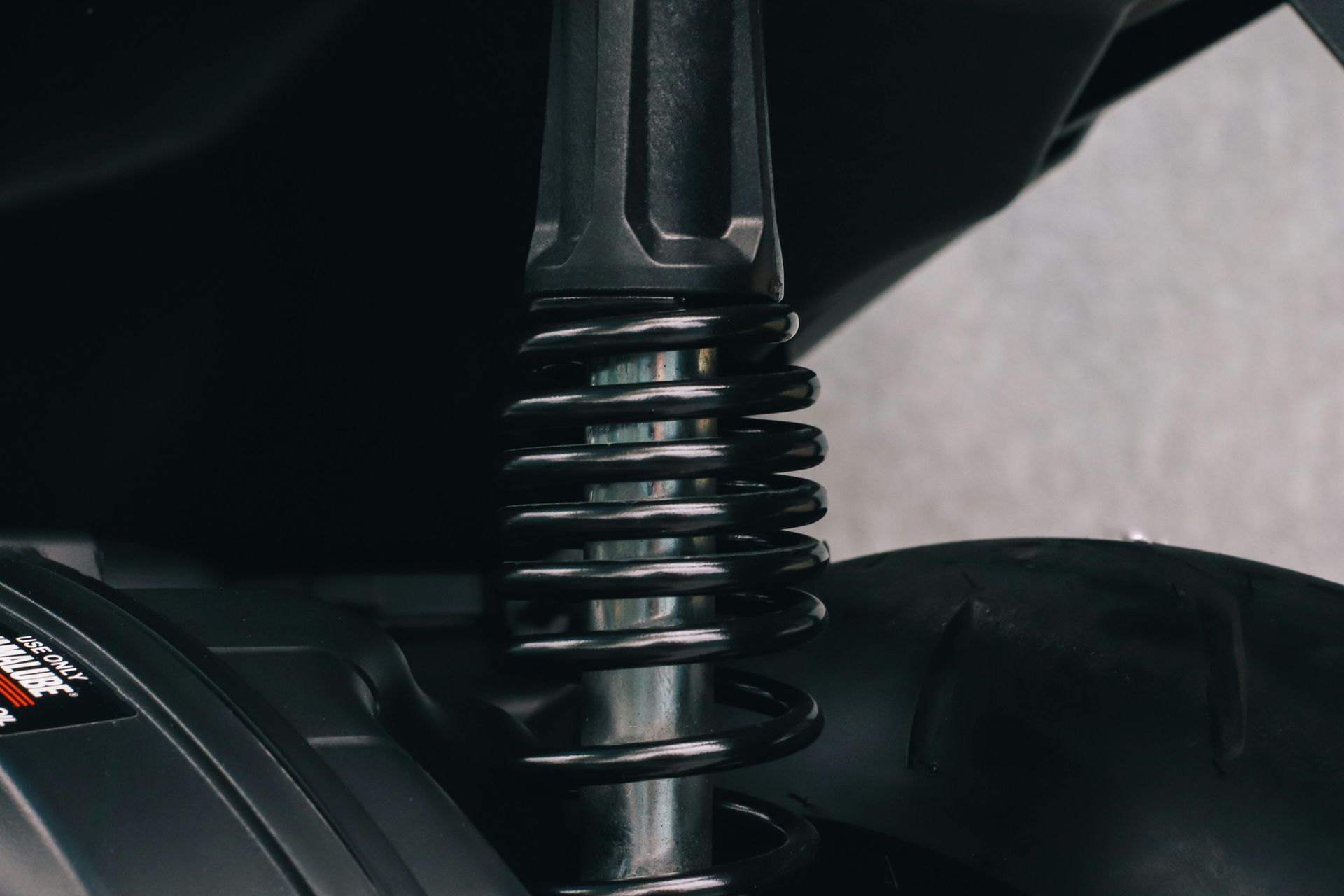 Black shock absorber with coil spring, part of a vehicle's suspension system.