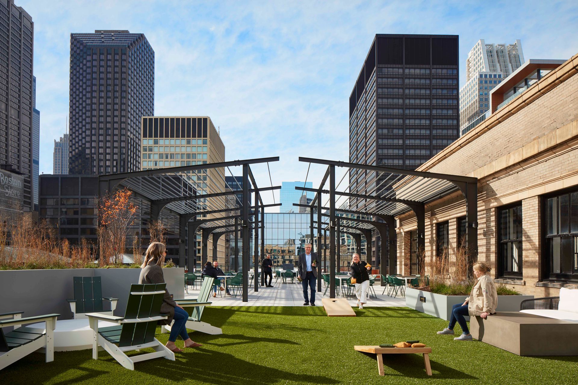 A group of people are playing a game of cornhole on a rooftop.