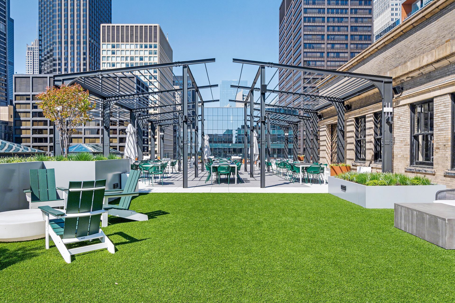 A rooftop garden with chairs and tables in the middle of a city.