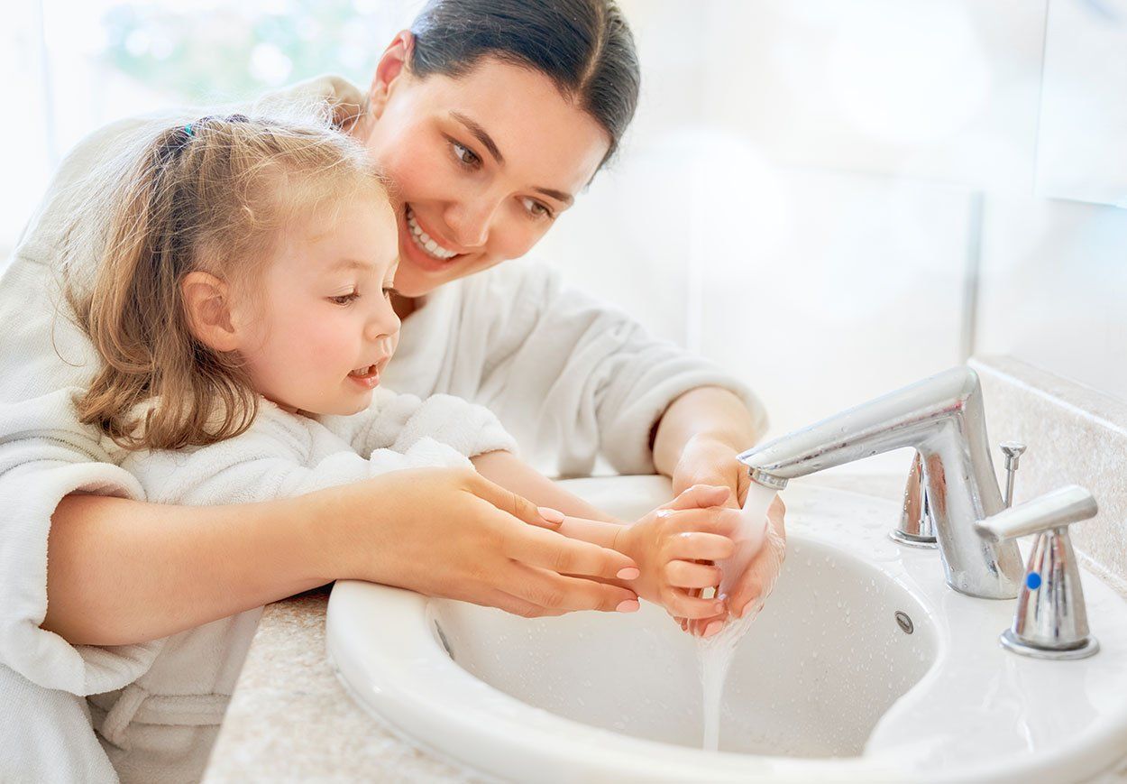 young girl and mom washing hands in white sink