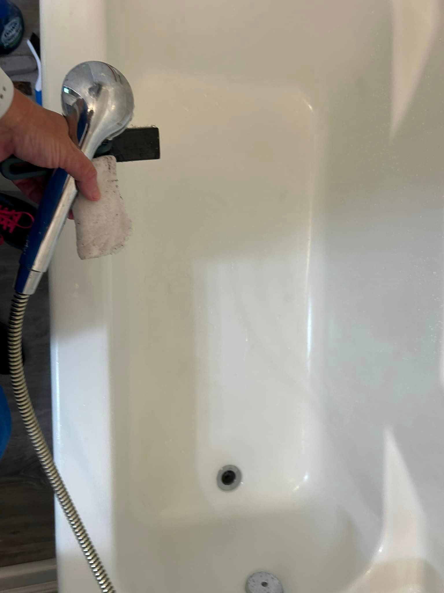 A person is holding a shower head over a bathtub.